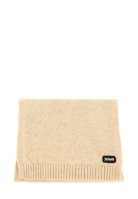 Écharpe en tricot beige pliée avec des bords côtelés et une petite étiquette en tissu noire Schott New York dans un coin.
