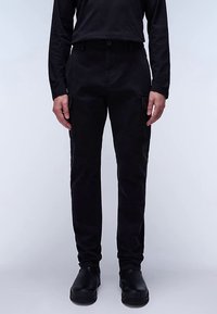 Black cargo pants made of sturdy fabric, featuring side pockets, a fitted waist, and a tapered leg design. Worn with black slip-on shoes.