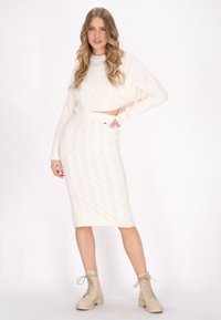 Witte gebreide cropped trui met een gestructureerd ruitpatroon, gecombineerd met een bijpassende rok tot de knie. Beige veterschoenen maken de outfit compleet.