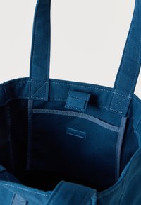 Μπλε τσάντα ώμου από ύφασμα με ενισχυμένους ιμάντες και εσωτερική τσέπη, με μια μικρή ετικέτα Calvin Klein στο εσωτερικό.