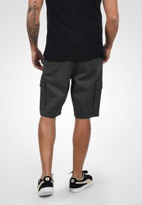 Sötétszürke anyagból készült cargo short, térd fölötti hosszúsággal, két oldalsó zsebbel, gombos fedéllel és sima, egyszínű textúrával.