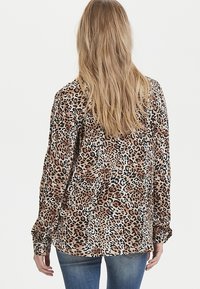 Blusa con stampa leopardata caratterizzata da maniche lunghe, polsini con bottoni e un tessuto liscio e leggero. La vista dal retro mette in evidenza una vestibilità comoda.