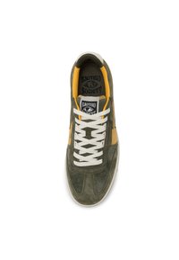 Zapatilla verde oliva con detalles amarillos, materiales de cuero ante y malla, punta redondeada, cordones blancos y logotipo de la marca en la plantilla.