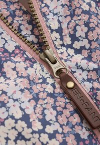 Blommönstrad tyg i lila och rosa nyanser med en mässingsdragkedja och läderdragflik. Har delikata blommönster över hela.