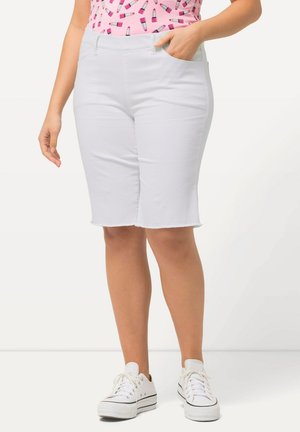 Bermudas de denim blanco con bolsillos frontales y dobladillo sin terminar. Combinadas con una blusa de estampado rosa y zapatillas blancas. Diseño casual y ajustado.