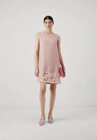 Αφόρετο ροζ φόρεμα με δαντελένιο στρίφωμα, με χαλαρή εφαρμογή. Συνδυάζεται με ροζ τσάντα και αντίστοιχα μυτερά παπούτσια. Λείο υλικό.