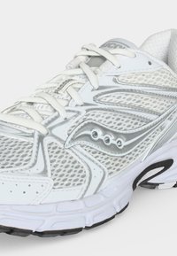 Λευκό και ασημί δίχτυ αθλητικό παπούτσι με λευκά κορδόνια, μαξιλαρωτή σόλα και λογότυπο της μάρκας στην πλευρά, τοποθετημένο υπό γωνία για να δείχνει το μπροστινό και το εξωτερικό μέρος.