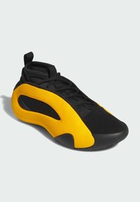Zwarte en gele sportschoen met een strak ontwerp, voorzien van een bovenwerk van mesh, een ronde neus en een opvallend uitgesneden gedeelte aan de zijkant.