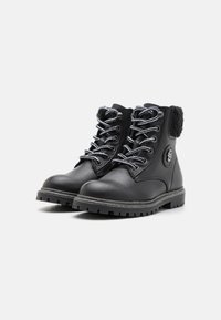 Botas de cuero negras hasta el tobillo con suelas de goma gruesas, cordones con patrón, cremallera lateral y forro de felpa en el cuello, mostradas una al lado de la otra.