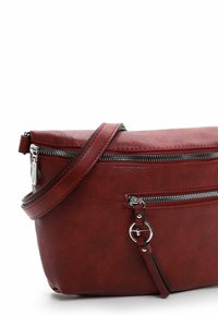 Červená kožená crossbody taška s hladkým povrchem, vybavená zipy v stříbrném odstínu, nastavitelným popruhem a přední kapsou.