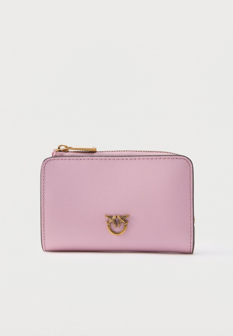 Ανοιχτό ροζ δερμάτινο πορτοφόλι με φερμουάρ σε χρυσό χρώμα και διακοσμητικό χρυσό έμβλημα με δύο πουλιά που κρατούν ένα δαχτυλίδι στο μπροστινό μέρος.