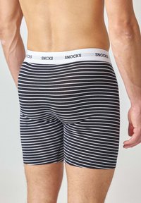 Boxer briefs a righe bianche e nere realizzati in tessuto morbido, dotati di una vita elastica bianca con il logo "SNOCKS".