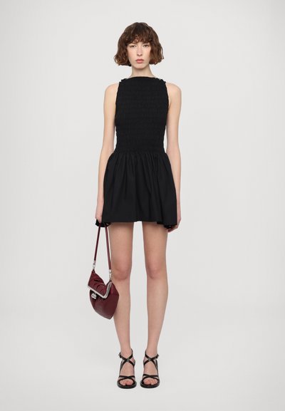 Black sleeveless dress with a smocked bodice and flared skirt. Paired with black strappy sandals and a small burgundy handbag.