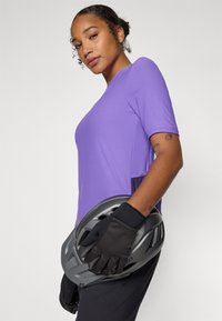 T-shirt de sport violet à manches courtes, en tissu texturé, associé à des gants noirs et à un casque de vélo gris. Design moderne et simple.