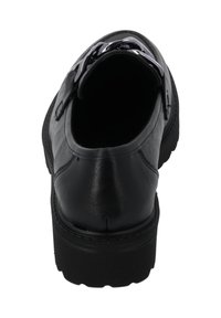 Chaussure en cuir noir avec un bout arrondi, semelle en caoutchouc noir épaisse, et accents métalliques décoratifs sur le devant. Texture lisse avec des détails de couture.