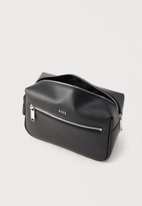 Juoda, tekstūruota odinė rankinė su viršutiniu užtrauktuku ir priekinė kišene su užtrauktuku. Puošta prekės ženklo ženklinimu ir sidabrinės spalvos dekoratyvinėmis detalėmis.