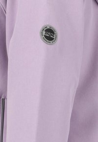 Hellblaues Jackett aus strukturiertem Stoff mit einem runden grauen Logo am linken Ärmel. Sauberes Design mit minimalen Akzenten.