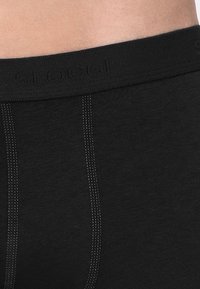 Boxer briefs neri in cotone con waistband elastico marchiato, caratterizzati da cuciture piatte e una consistenza liscia. Design semplice e funzionale.