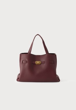 Sac à main en cuir bordeaux foncé avec deux poignées et une petite boucle rectangulaire dorée à l'avant, présenté sur un fond clair uni.