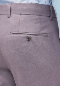 Približna slika vijoličnih hlač z gumbom na zadnjem žepu in zankami za pas, oblečenih s svetlo modro srajco.