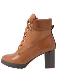 Bota de tobillo de cuero marrón con diseño de cordones, ojales dorados y tacón grueso. Cuenta con un cuello acolchado y suela de goma texturizada.