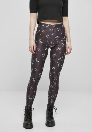 Leggings cu model floral, dintr-un material închis, cu talie înaltă. Prezintă desene colorate de flori pe un fundal negru. Asortate cu cizme negre.
