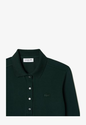 Polo de color verde oscuro con una tela texturizada, un cuello y tres botones. Presenta un logo bordado de Lacoste en el lado izquierdo.