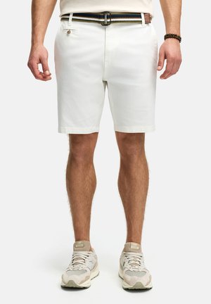 White cotton shorts with a straight fit, featuring a button, side pockets, and a multi-colored striped belt. Worn with light-colored sneakers.