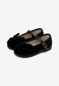 Zapatos de terciopelo negro con correa estilo Mary Jane, punta redondeada y detalle de lazo en la parte frontal. Talón reforzado y plantilla acolchada para mayor comodidad.