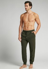 Olijfgroene joggerbroek met elastische tailleband, zijzakken en aansluitende boorden, gemaakt van zachte stof, met een trekkoordsluiting.