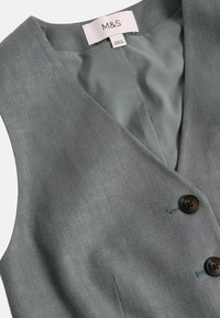 Grau meliertes Stoffweste mit glatter Textur, V-Ausschnitt-Design, zwei braunen Knöpfen und genähten Details, gekennzeichnet mit "M&S"-Etikett.