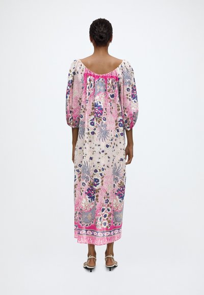 Mujer con un vestido largo y suelto con estampado floral en rosa, azul y blanco, con mangas abullonadas tres cuartos, de espaldas.