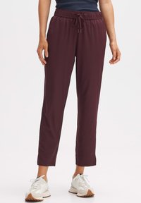 Bordeaux, lichte, elastische broek met een trekkoord in de taille. Ontwerp met rechte pijpen. Gecombineerd met witte sneakers met beige accenten.