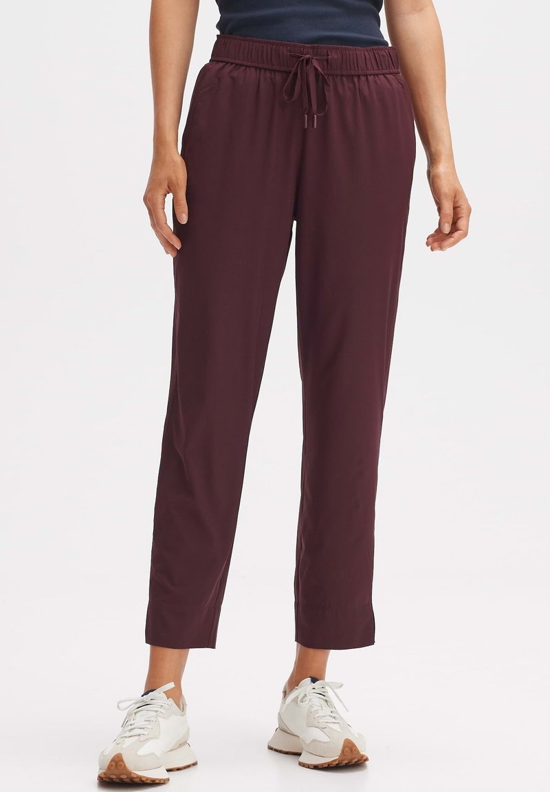 Bordeaux, lichte, elastische broek met een trekkoord in de taille. Ontwerp met rechte pijpen. Gecombineerd met witte sneakers met beige accenten.