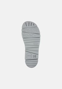Suola di scarpa in gomma grigia con un motivo di battistrada testurizzato, che include linee orizzontali e design a onda. Taglia contrassegnata come 38.