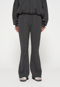 Grijze flared sweatpants gemaakt van een textuurrijk, zacht materiaal. Voorzien van een elastische tailleband en een klein logo detail aan de zijkant.