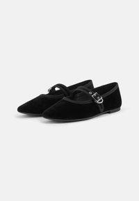 Ballerine in velluto nero con punta affusolata. Presentano una fascia decorativa con una fibbia argentata e una suola piatta. Texture liscia in tutto.