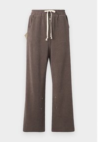 Brown sweatpants made of textured fabric, featuring a drawstring waistband, front pockets, and snaps at the ankles for adjustability.