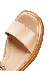 Infradito in pelle beige con una fascia larga, texture liscia e soletta imbottita. Cuciture discrete e suola in gomma offrono aderenza.