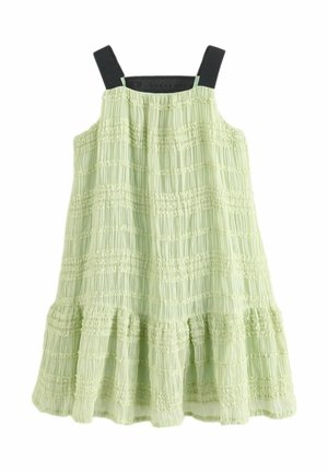Robe vert clair avec un design à volants, présentant une texture smockée, de fines bretelles et des accents noirs contrastants en haut.