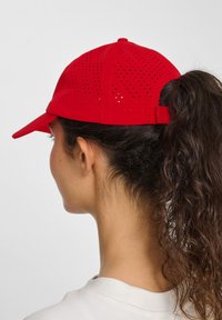 Rød hat med perforeret design, buet skygge, justerbar bagside og tekstureret overflade. Velegnet til forskellige udendørs aktiviteter.