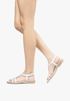 Sandali bianchi in pelle con suola in legno piatta, caratterizzati da un design con cinturino incrociato e una fibbia decorativa sulla caviglia.
