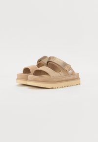 Tan suède sandalen met stoffen banden en een getextureerde, tan rubberen buitenzool. Beschikt over een open teen en een gevoerde voetbed voor comfort.