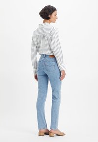 Svetlo modri skinny jeans iz denima, z visokim pasom in prišite zadnje žepe. V kombinaciji z majico s črtastim vzorcem in gumbi.