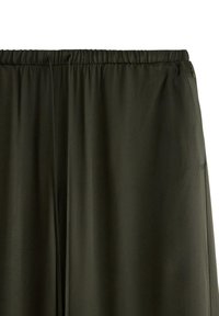 Pantaloni leggeri di colore verde scuro, con vita elastica, dalla texture liscia e dotati di tasche laterali, progettati per comfort e libertà di movimento.