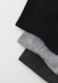Drei Paar Socken gestapelt: schwarz, grau und dunkelgrau. Sie haben eine glatte, gestrickte Textur mit gerippten Bündchen.