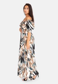 Maxiklänning med off-shoulder-design, prydd med ett blommönster i teal, brunt och svart på en ljus bakgrund. Rynkad midja och flödande tyg.
