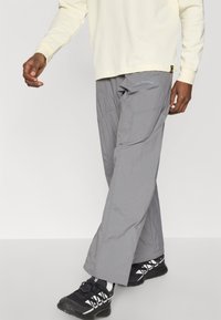 Γκρι εξωτερικό παντελόνι με ελαφρύ, ανθεκτικό στο νερό υλικό και άνετη εφαρμογή. Διαθέτει διακριτικό λογότυπο και πλαϊνές τσέπες για λειτουργικότητα.