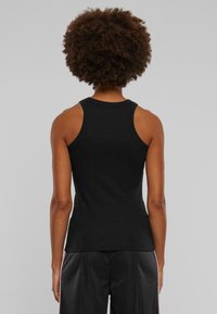 Top negru fără mâneci, cu guler rotund, design ajustat și material din bumbac moale. Textură netedă, fără modele sau accente vizibile.