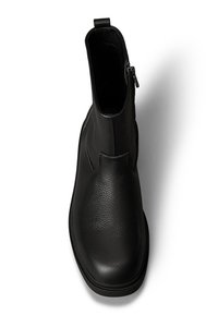 Czarny skórzany botek za kostkę o gładkiej teksturze, zaokrąglonym nosku i bocznym zamku błyskawicznym. Posiada niewielki obcas i minimalistyczny design bez ozdób.